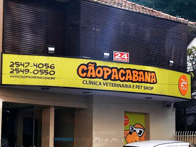 Fachada da Cãopacabana com o letreiro amarelo de clínica veterinária e pet shop 24 horas